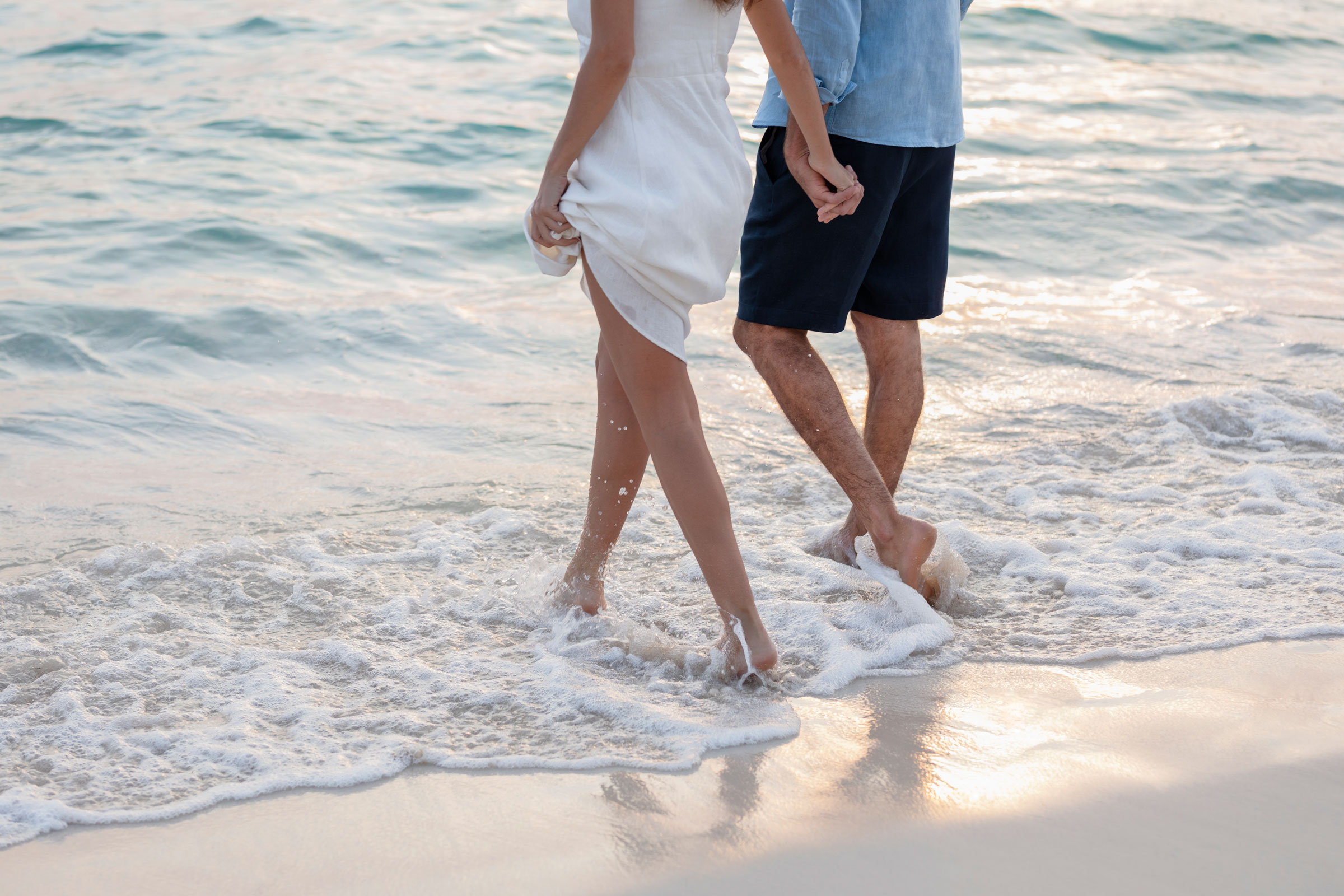 Couple holding hands and walking along a beach in Playa Mujeres Couple holding hands and walking along a beach in Playa Mujeres