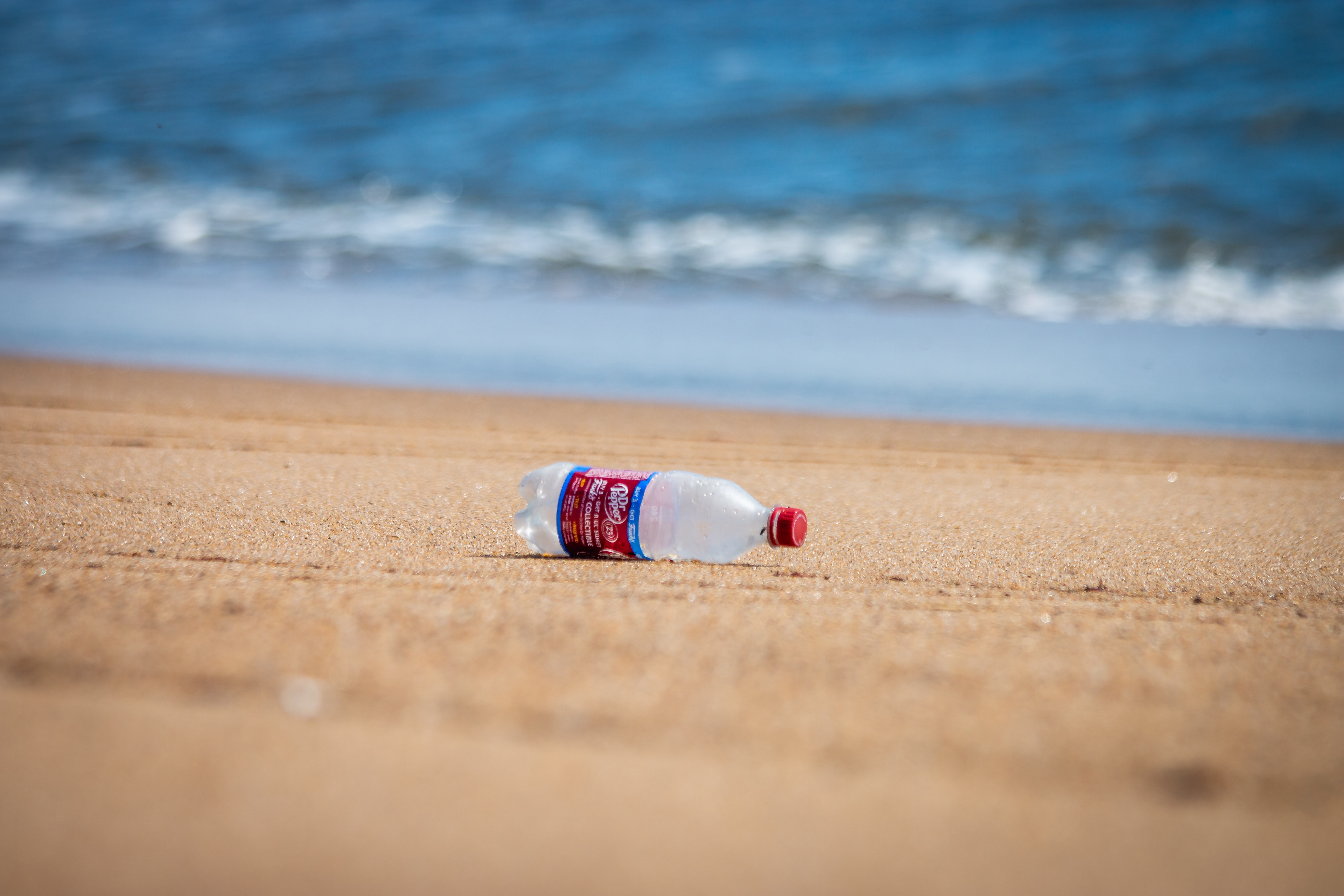 Leave no trace principle demonstrated by a plastic bottle on the sand ready to be picked up
